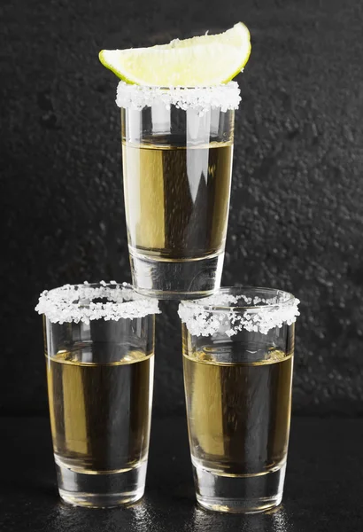 Tequila com sal e limão sobre um fundo escuro — Fotografia de Stock