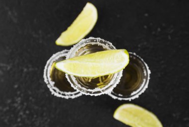 Koyu arkaplanda tuz ve limonlu tekila.
