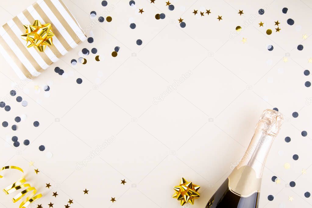 Holiday attributes. Bottle of champagne, confetti and gift for new year on  beige background. Top view. Copy space