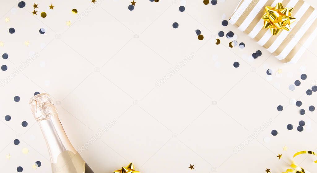 Holiday attributes. Bottle of champagne, confetti and gift for the new year on  beige background. Top view. Copy space