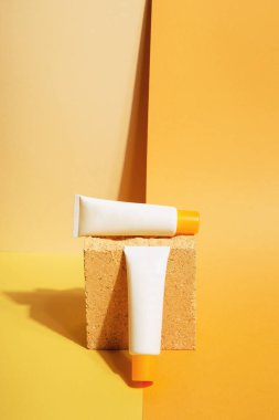 Turuncu arka planda beyaz güneş kremi tüpleri. Güneş koruması. Boşluğu kopyala