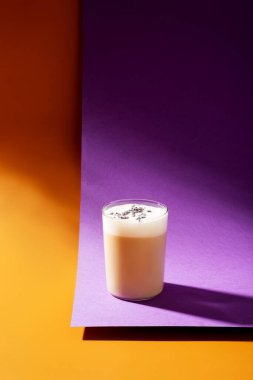 Mor arka planda latte içmek güneş ışığı ve sert gölgeler