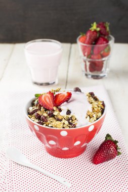 Granola with strawberry, nuts and yogurt on a wooden background