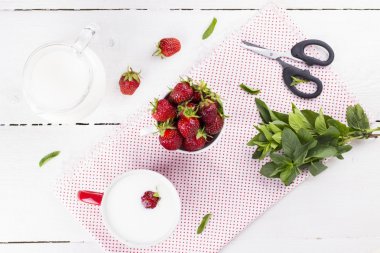 Kase çilek, cam ve süt ile sürahi ile beyaz üzerine nane woo