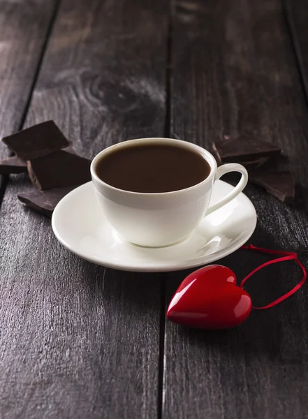 Cacau quente em uma caneca branca com fatias de chocolate e coração vermelho — Fotografia de Stock