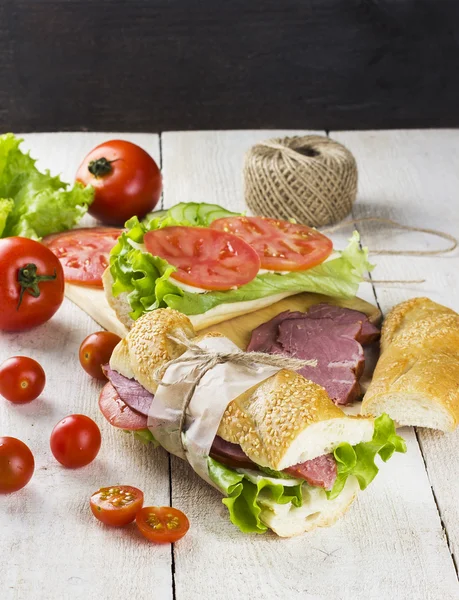 Sandwich with sesame bread, tomato, cucumber, meat, cheese, lett — Stock Photo, Image