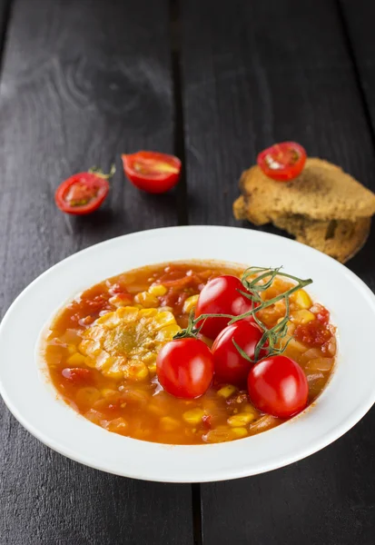 Corn soup with cherry tomatoes in white plate against a dark bac — Stockfoto