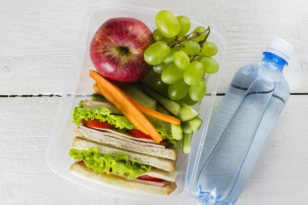 Lunchbox sendvič, zeleniny a ovoce, láhev vody na bílém pozadí — Stock fotografie