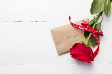 Kırmızı gül, aşk mesajı Beyaz ahşap zemin üzerinde
