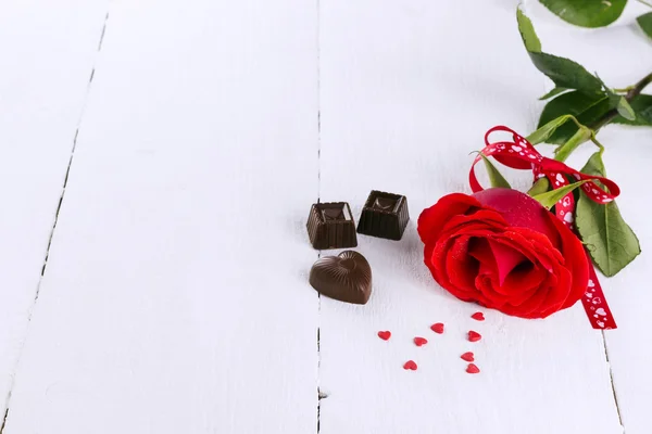 Rose rouge, chocolats sur fond de bois blanc — Photo