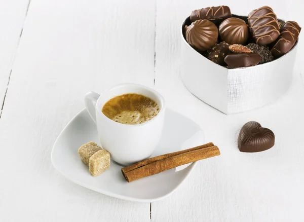 Tasse Kaffee und Pralinenschachtel auf weißem Holzgrund — Stockfoto