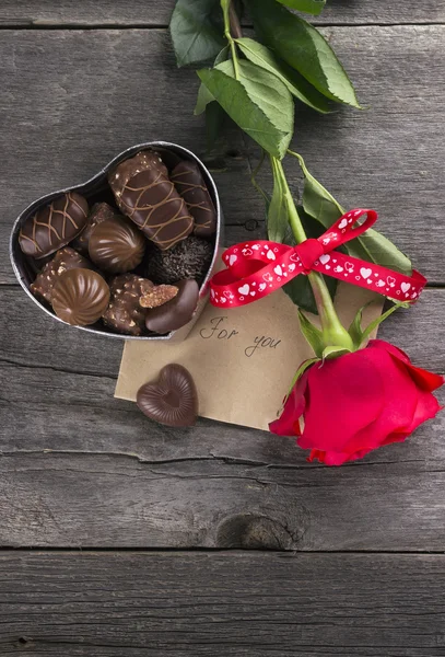 Box of chocolates, red rose on a dark background