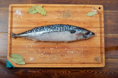 Üstten baharatlar ile ahşap plaka üzerinde bir uskumru