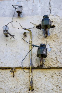 Yirminci yüzyılın sonlarından kalma seramik elektrik yalıtıcıları daha eski bir duvarda.