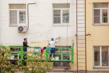 İnşaat işçileri, yirminci yüzyılın dış cephesinde büyük onarımlar yapmaya çalışıyorlar.