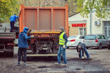 İnşaat işçileri kalan asfaltı yüklüyor.