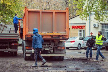 İnşaat işçileri kalan asfaltı yüklüyor.