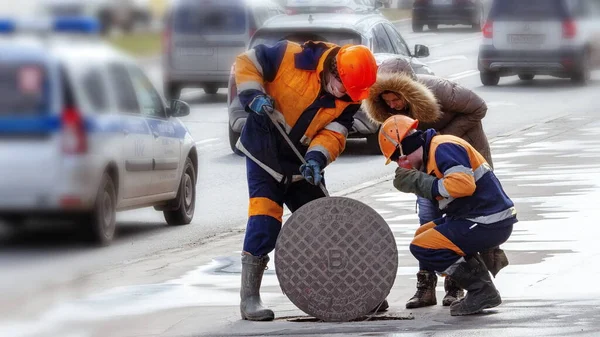 Sewer service workers check the manhole
