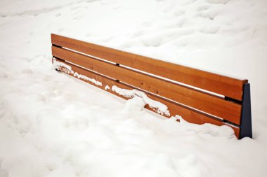 The benches are dusted with snow - only their backs stick out