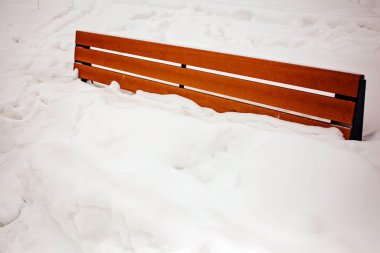 The benches are dusted with snow - only their backs stick out