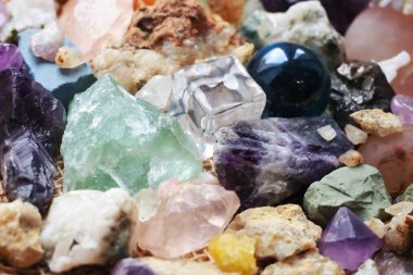 Şeffaf plastikten yapılmış bir kübik figür ve fosillerin yanında camdan yapılmış bir top figürü ve çeşitli kayaların mineralleri.