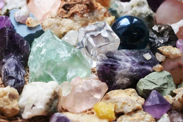 Şeffaf plastikten yapılmış bir kübik figür ve fosillerin yanında camdan yapılmış bir top figürü ve çeşitli kayaların mineralleri.