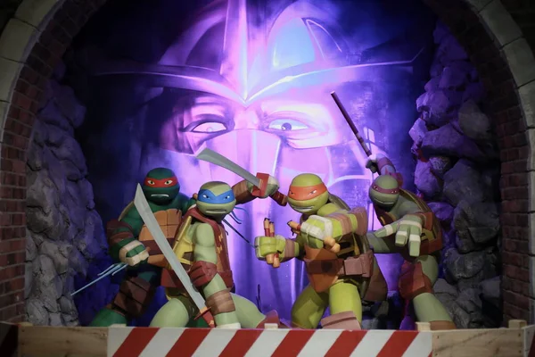 Genç Mutant Ninja Kaplumbağalar dörtlüsü ve arkadan Shredder.