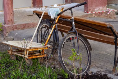Oturmak için bir bank parçası, bir bisiklet, bir çanta ve bir el arabası.