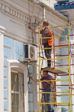 İki ressam Novorossiysk 'teki Rus tren istasyonunun ön cephesinin bir parçasını boyuyor.