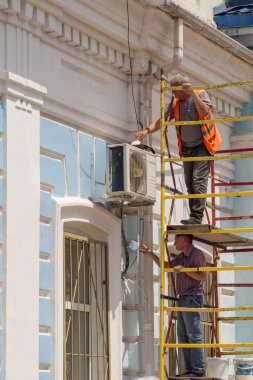İki ressam Novorossiysk 'teki Rus tren istasyonunun ön cephesinin bir parçasını boyuyor.