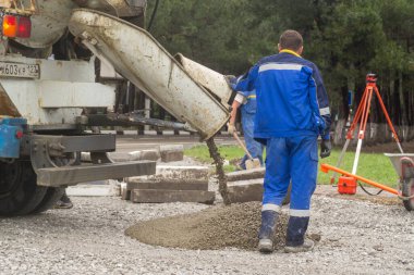 İnşaatçılar beton karışımı yapar ve temelleri doldurur.