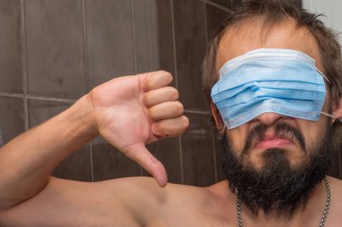 Adam gözlerini kapatırken yüzüne maske takmış ve ondan hoşlanmadığını göstermiş.