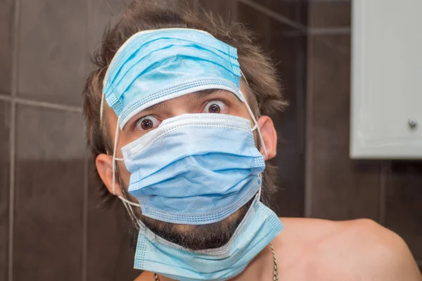 Ein Überraschter Junger Bärtiger Mann Mit Drei Medizinischen Masken Auf — Stockfoto