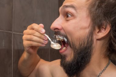 Sakallı bir adam bıyığını sürerken ekşi krema yer.