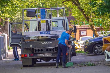 Bir hademe özel bir kamyonun yanında süpürüyor.