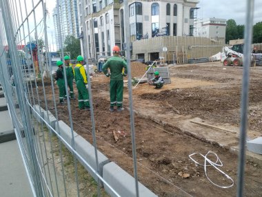 Çitin arkasında yeşilli binalar var.