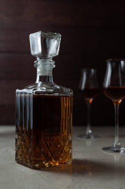 Alkollü kavanoz ve iki bardak. Viski, konyak, brendi, şeri ya da mermer masanın üstünde karanlık bir ruh halinde konyak olabilir..