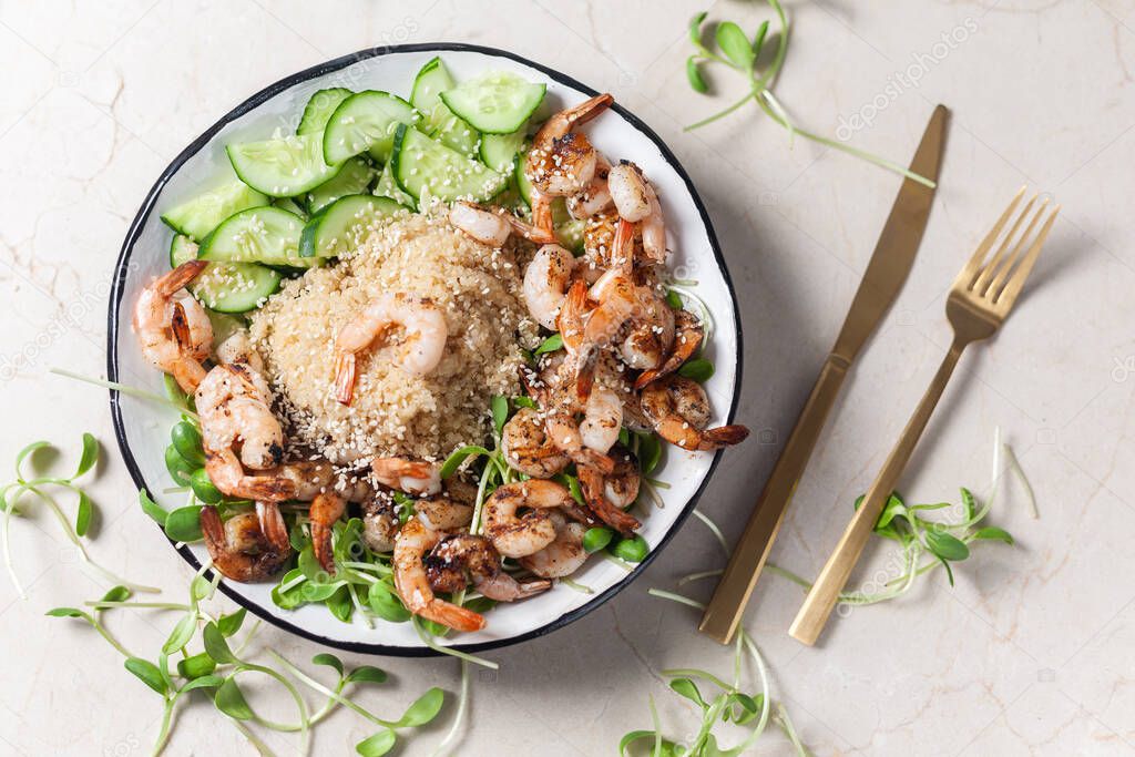 Quinoa with grilled prawns or shrimps, cucumber and micro greens on the marble background.