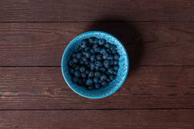Böğürtlenler mavi kasede, tahta arka planda..