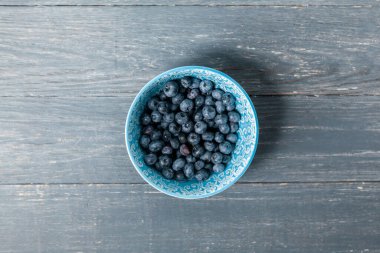 Böğürtlenler mavi kasede, tahta arka planda..