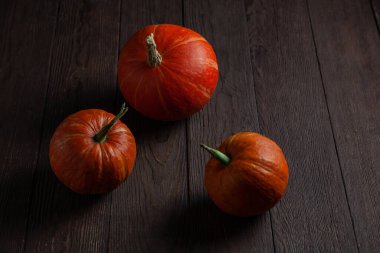 Ahşap masadaki balkabakları karanlık bir ruh halinde.