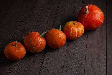 Beş balkabağı arka arkaya ahşap masanın üstünde karanlık bir ruh halinde..