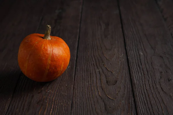 Pumpkin on wooden table in dark mood with copy space. — Stock Photo, Image