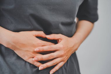 Karın bölgesini iki eliyle bastıran kadının yakın çekimi, ağrı veya kramplar gösteriyor, tıbbi, sağlık ve sağlık durumları için uygun..