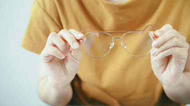 Bulanık lensli gözlük tutan kişi görme sorunu ve görüş konsepti gösteriyor. Göz bakımı, oftalmoloji, optik ölçü ve görüş düzeltme teması için optik gözlük sunan elleri kapatın.