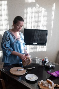 Geleneksel giyinmiş kadın ekmek, salo ve borscht ile akşam yemeği yiyor.