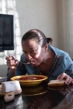 Geleneksel giyinmiş kadın ekmek, salo ve borscht ile akşam yemeği yiyor.