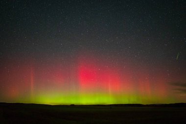 Kuzey ışıkları ve ufukta parlayan bir göktaşıyla göz kamaştırıcı bir gece manzarası. Huzurlu ve büyülü doğal güzellik