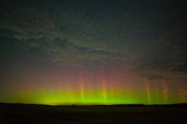 Kuzey ışıkları ve ufukta parlayan bir göktaşıyla göz kamaştırıcı bir gece manzarası. Huzurlu ve büyülü doğal güzellik