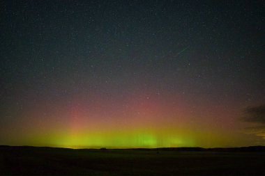 Kuzey ışıkları ve ufukta parlayan bir göktaşıyla göz kamaştırıcı bir gece manzarası. Huzurlu ve büyülü doğal güzellik